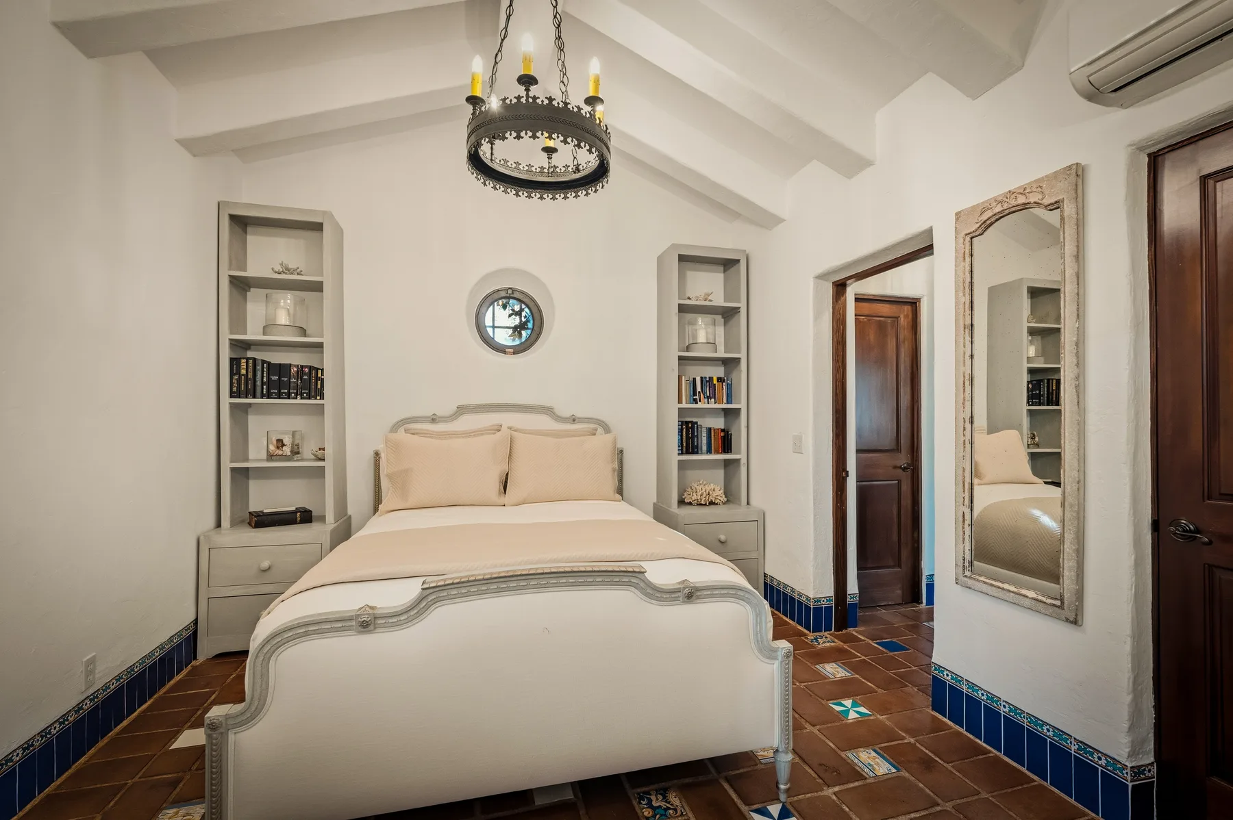 Un dormitorio con una cama, estantes empotrados y un espejo de pared.