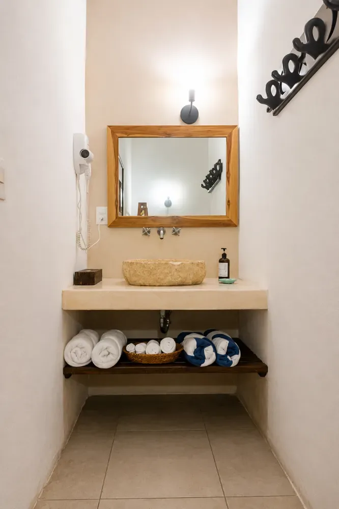 Baño con espejo, lavabo, toallas y secador de pelo montado en la pared.