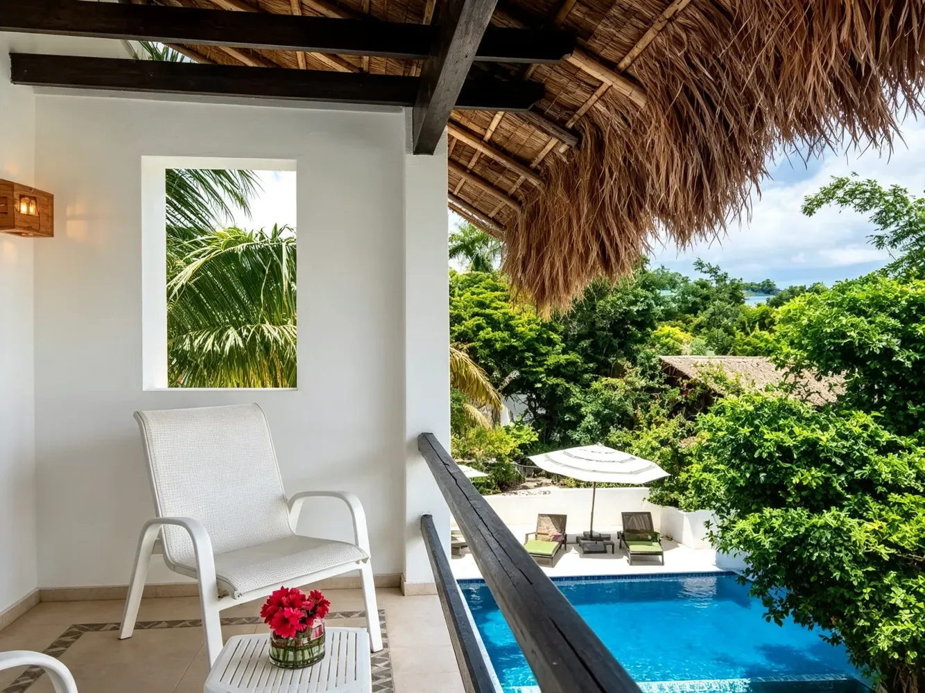 Balcón con una mesa y sillas con vistas a la piscina y la vegetación.