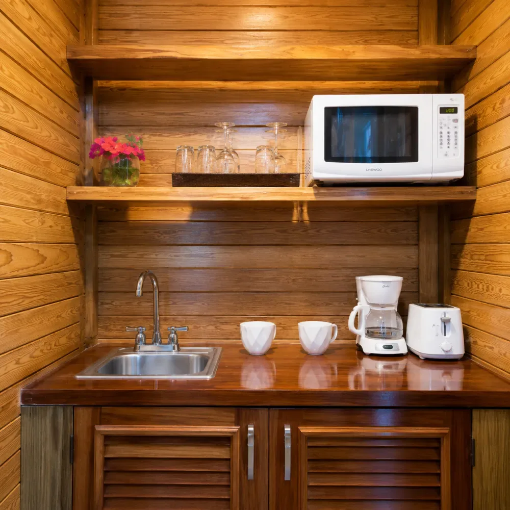 Cocina pequeña revestida de madera con fregadero, microondas, cafetera y tostadora.