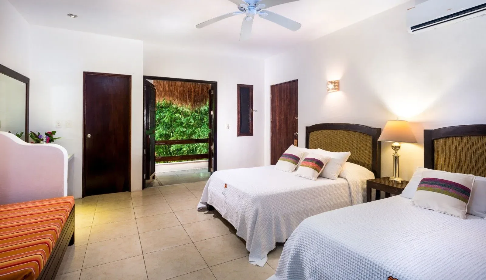 Dormitorio con dos camas individuales y una puerta abierta hacia la vegetación.