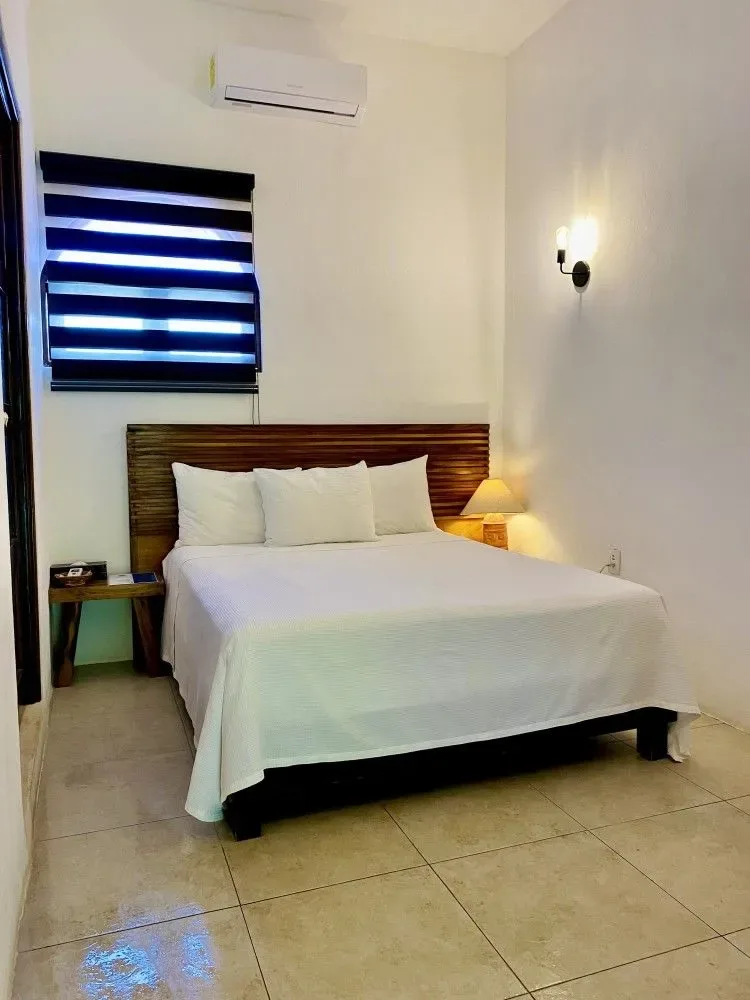 Dormitorio con una cama hecha y una persiana a rayas.