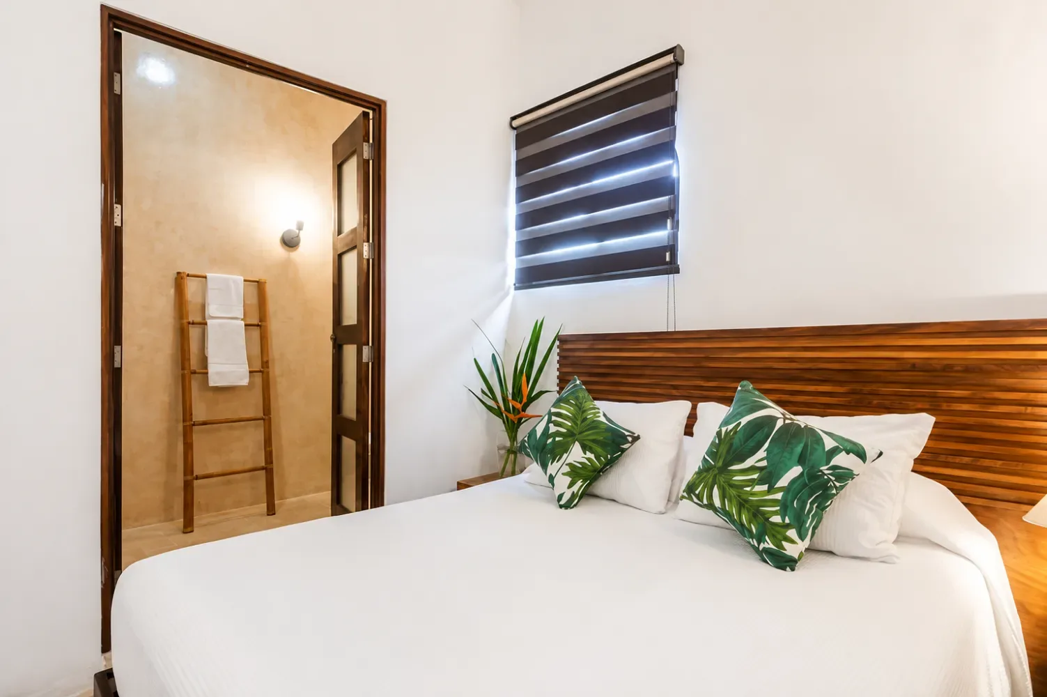 Bright bedroom with a white bed and wooden headboard.