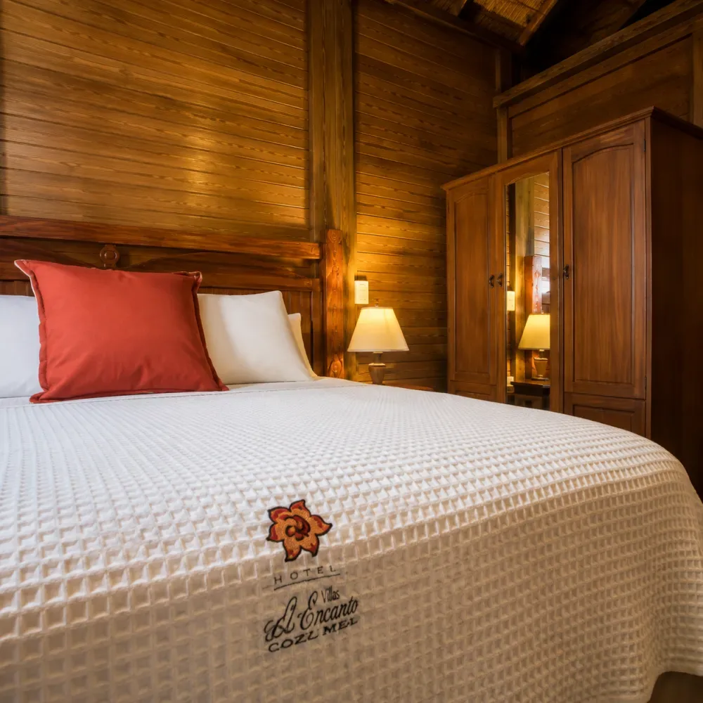 Dormitorio revestido de madera con una cama hecha y una lámpara de noche.
