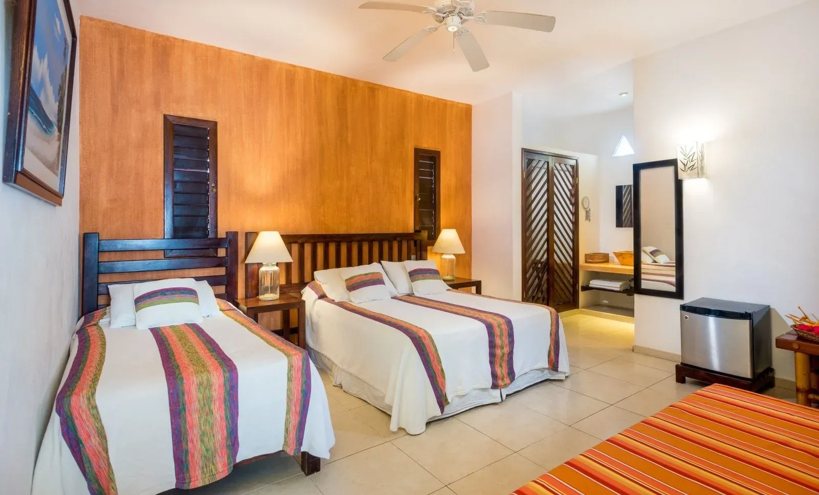 Hotel room with two beds, a wood accent wall, and tiled flooring.