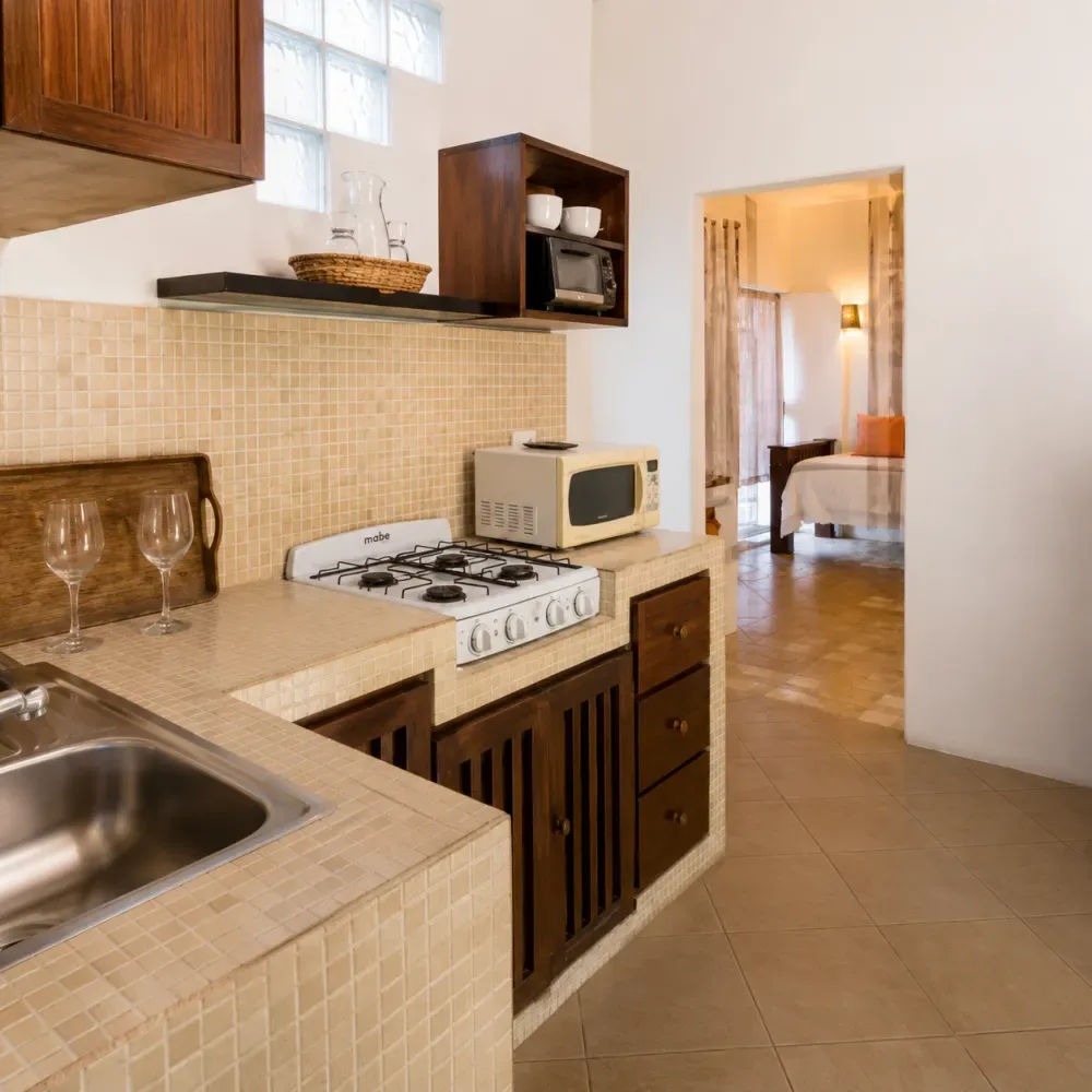 Cocina con azulejos, estufa, fregadero y microondas.