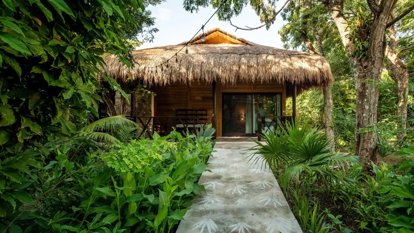 Bungaló tropical con techo de paja y sendero de jardín.