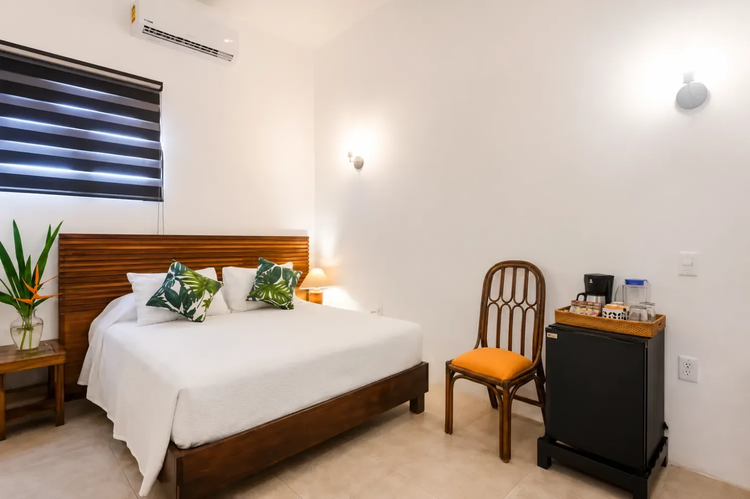 Dormitorio con una cama de madera, ropa de cama blanca y persianas.
