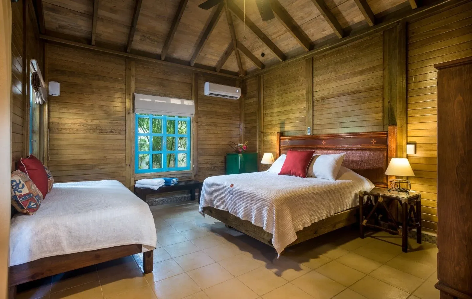 Dormitorio rústico con dos camas y paredes revestidas de madera.