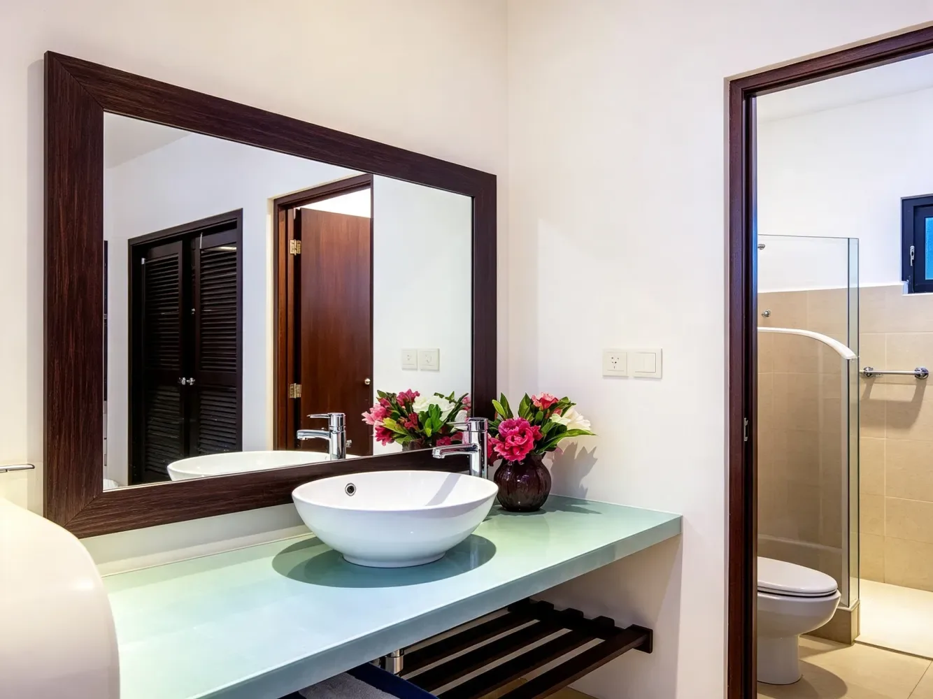 Mueble de baño con lavabo redondo y puerta de ducha de vidrio.