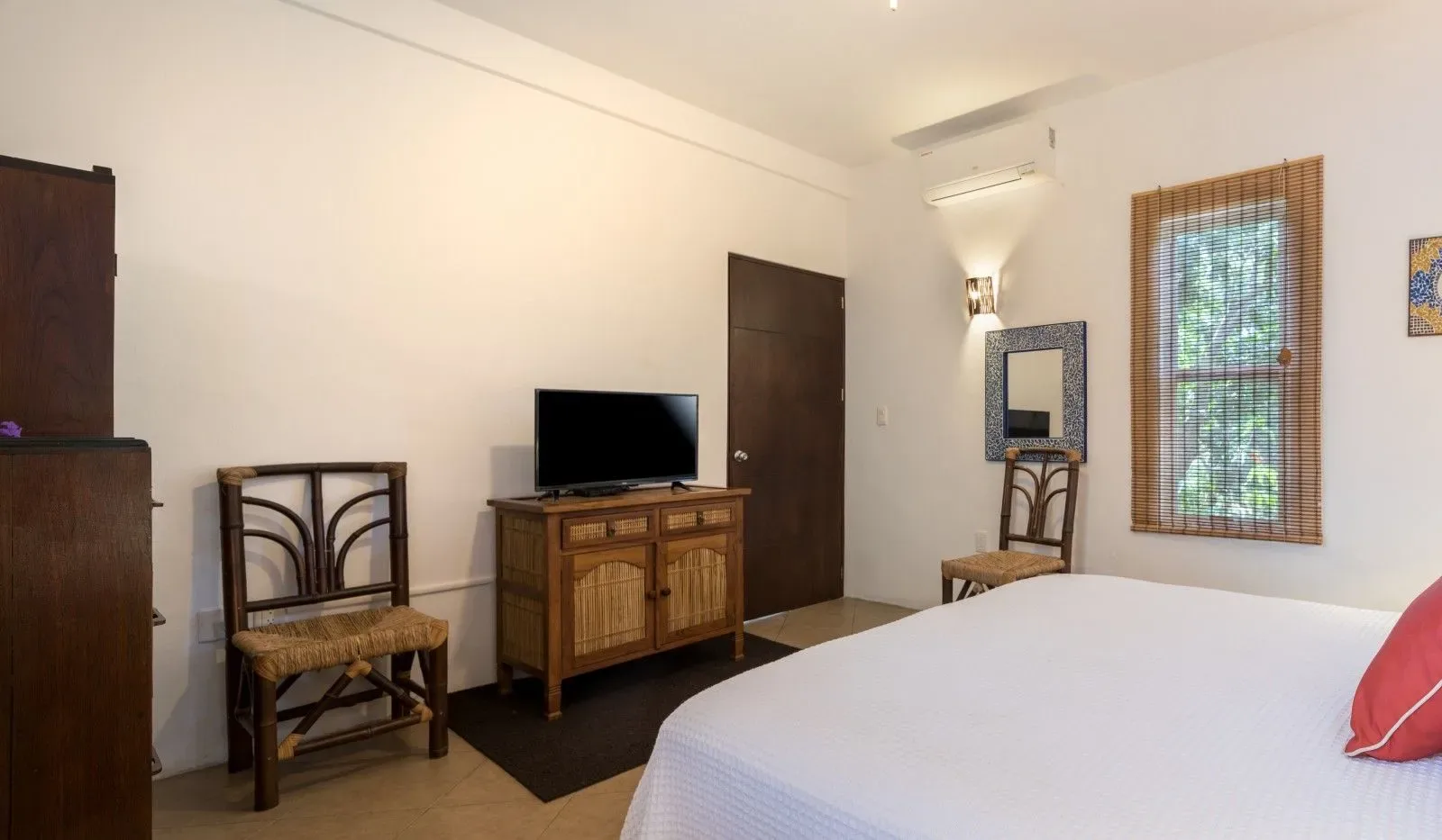 Dormitorio con cama, cómoda, televisor y sillas.
