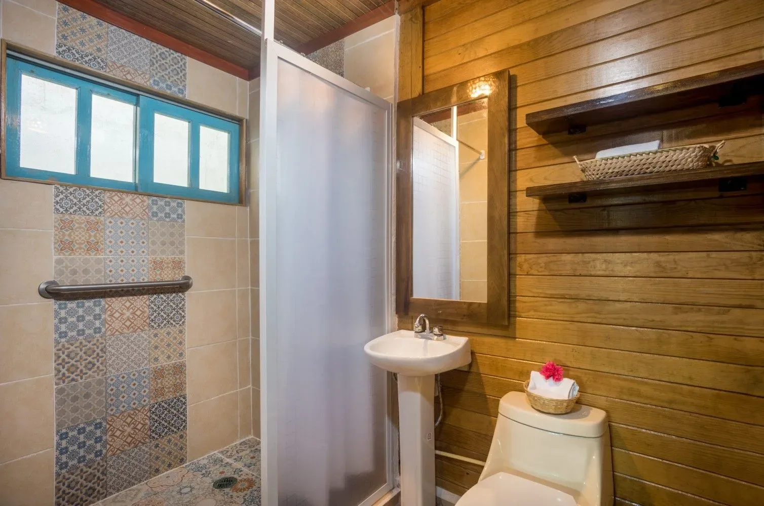 Baño pequeño con ducha, lavabo y paredes revestidas de madera.