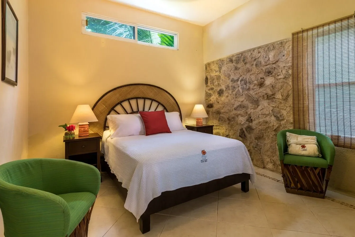 Dormitorio con una cama, sillas verdes y lámparas de noche.