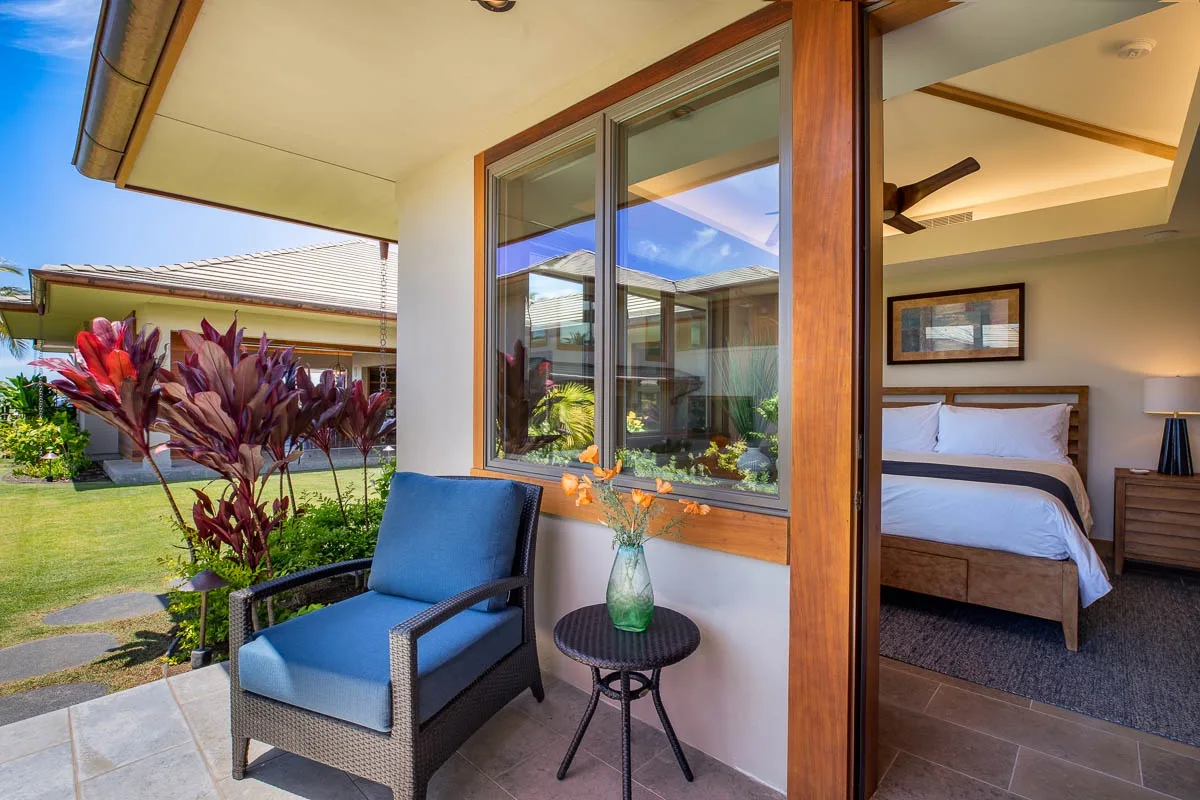 A bedroom opens onto a covered patio with seating and a small table.