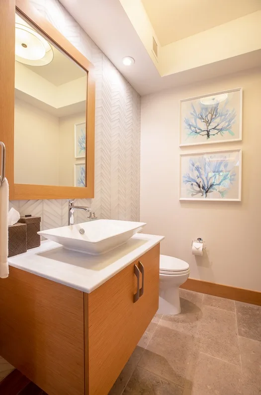 A bathroom with a sink vanity, toilet, and framed floral artwork.