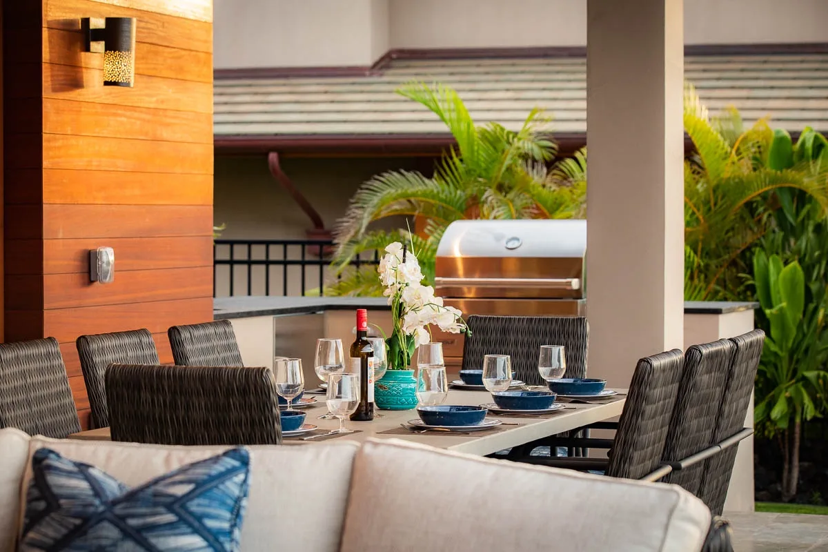 An outdoor dining area with a set table and a built-in grill.