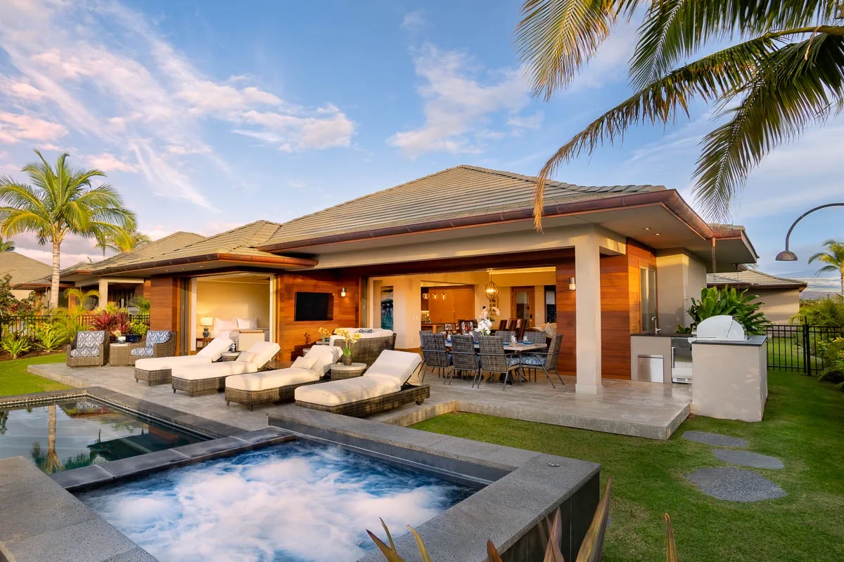 A modern single-story home opens onto a patio with outdoor seating and a pool.