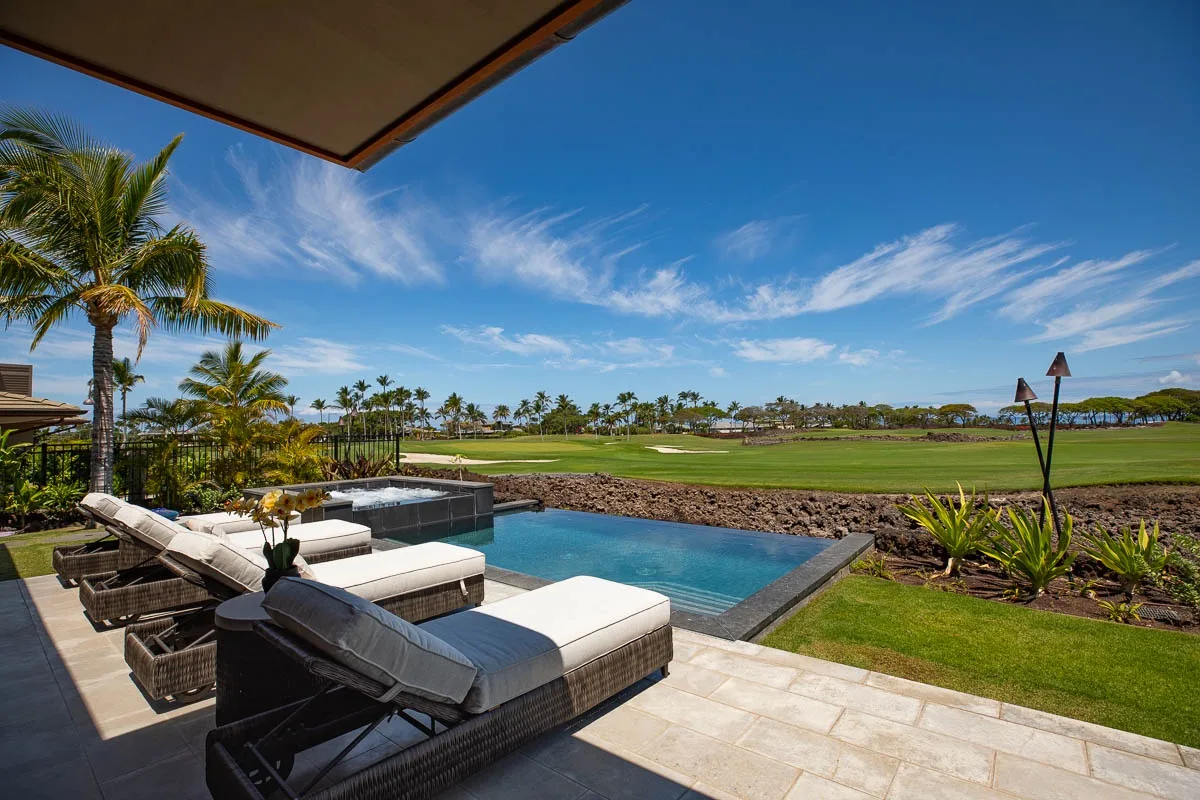 A patio overlooks a swimming pool and a broad green landscape.