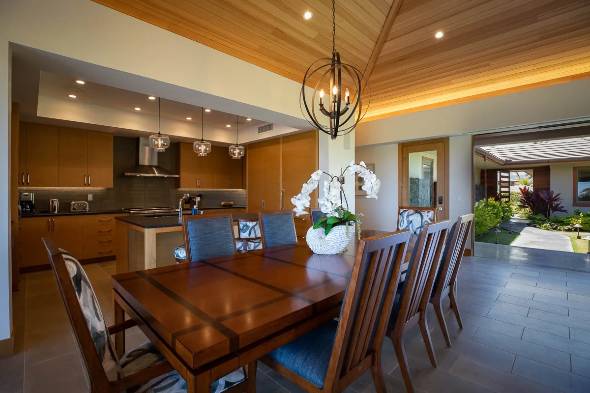 A dining area with a wooden table and chairs beside an open kitchen.