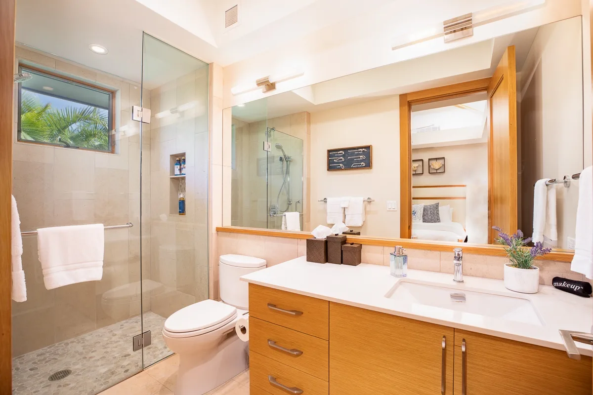 A bright bathroom with a glass shower and a wide vanity.