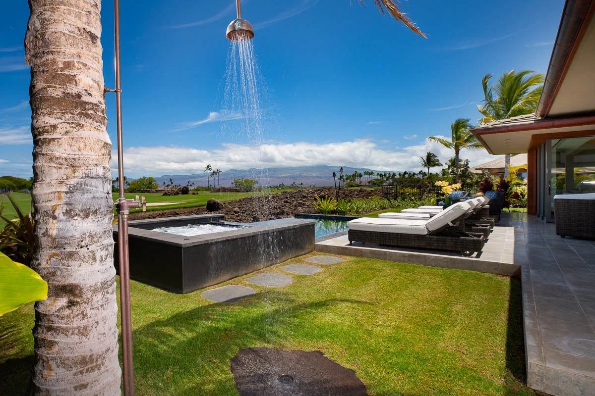 An outdoor patio with a raised spa, lounge seating, and a garden shower.