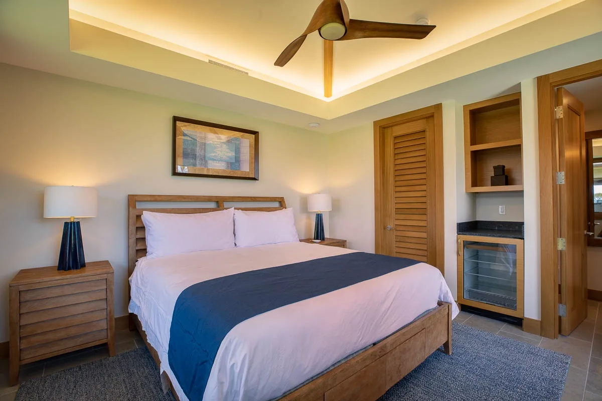 A bedroom with a large bed, bedside tables, and a ceiling fan.