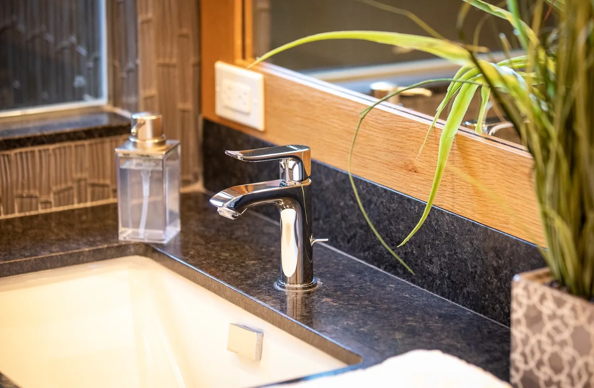 A bathroom sink with a chrome faucet sits beneath a wide mirror.