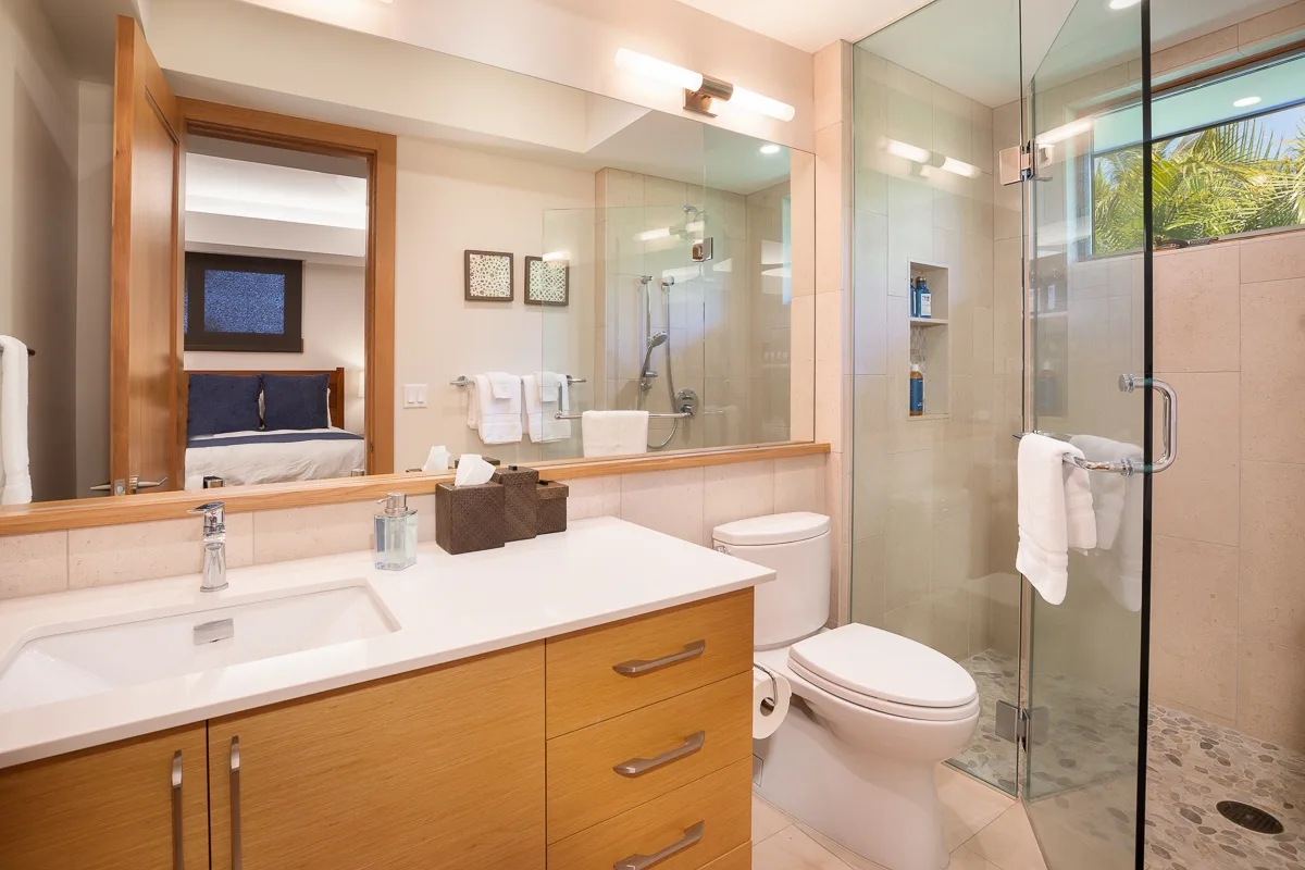 A bright bathroom with a vanity, toilet, and glass shower.