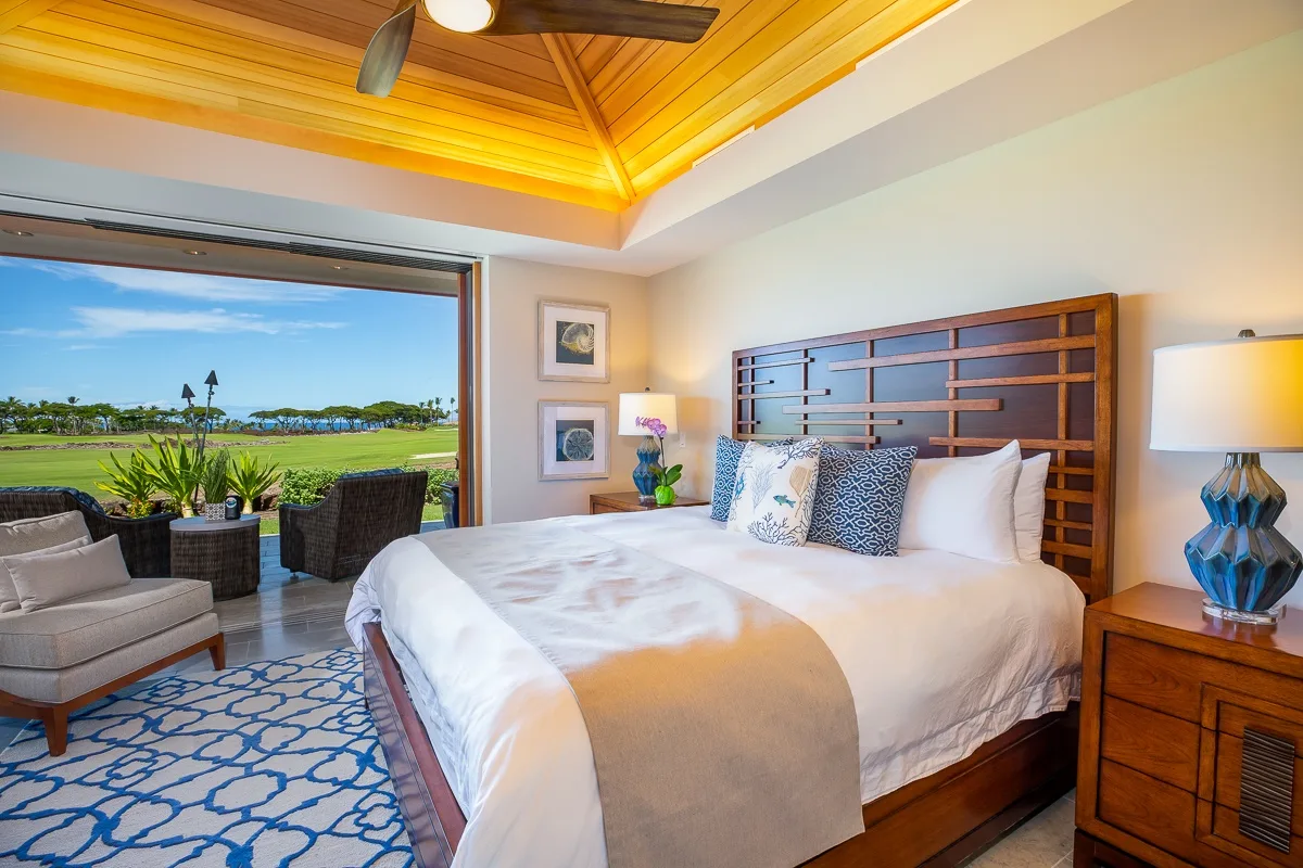 A bedroom with a large bed and a sliding glass door opening to a patio.