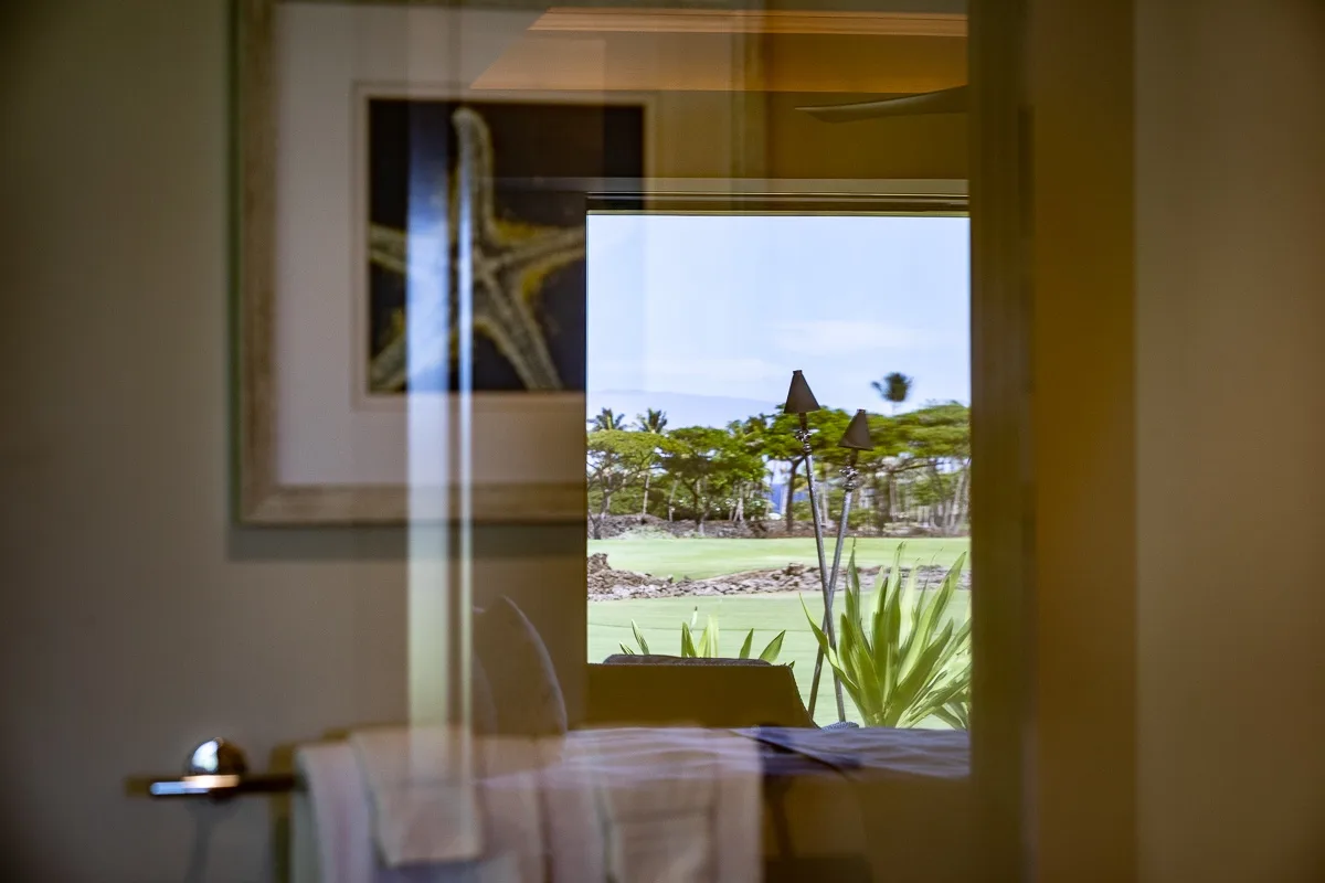 A room overlooks a landscaped golf course through a large window.