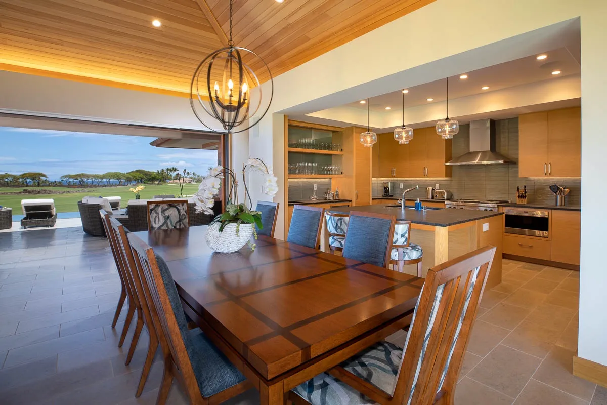 A dining area opens onto a kitchen, with a large table and sliding glass doors.