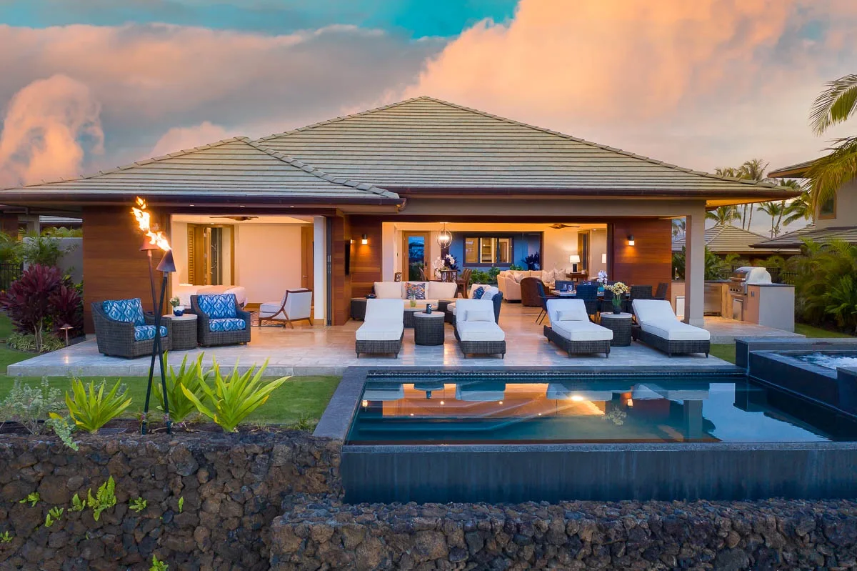 Una casa moderna da a un patio con asientos junto a una piscina.