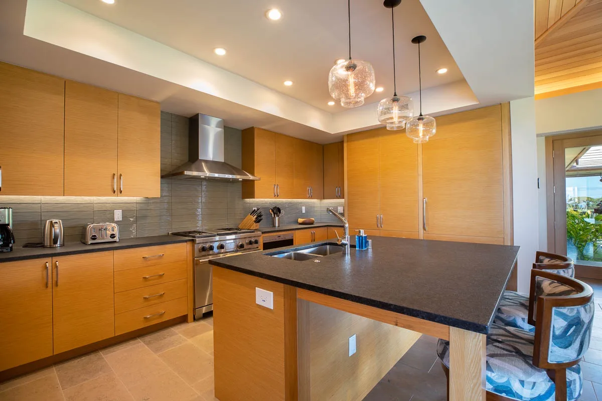 A modern kitchen with wooden cabinets, a dark countertop, and a central island.