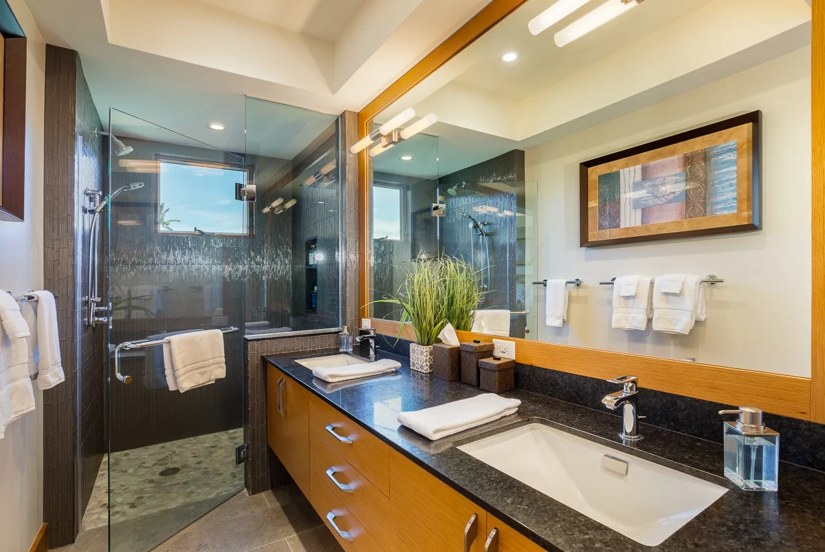 A bathroom with a glass shower and a vanity with a sink.