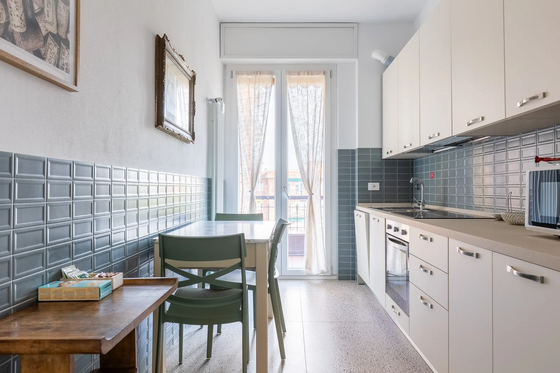 Una cocina estrecha con una mesa de comedor junto a ventanas altas.