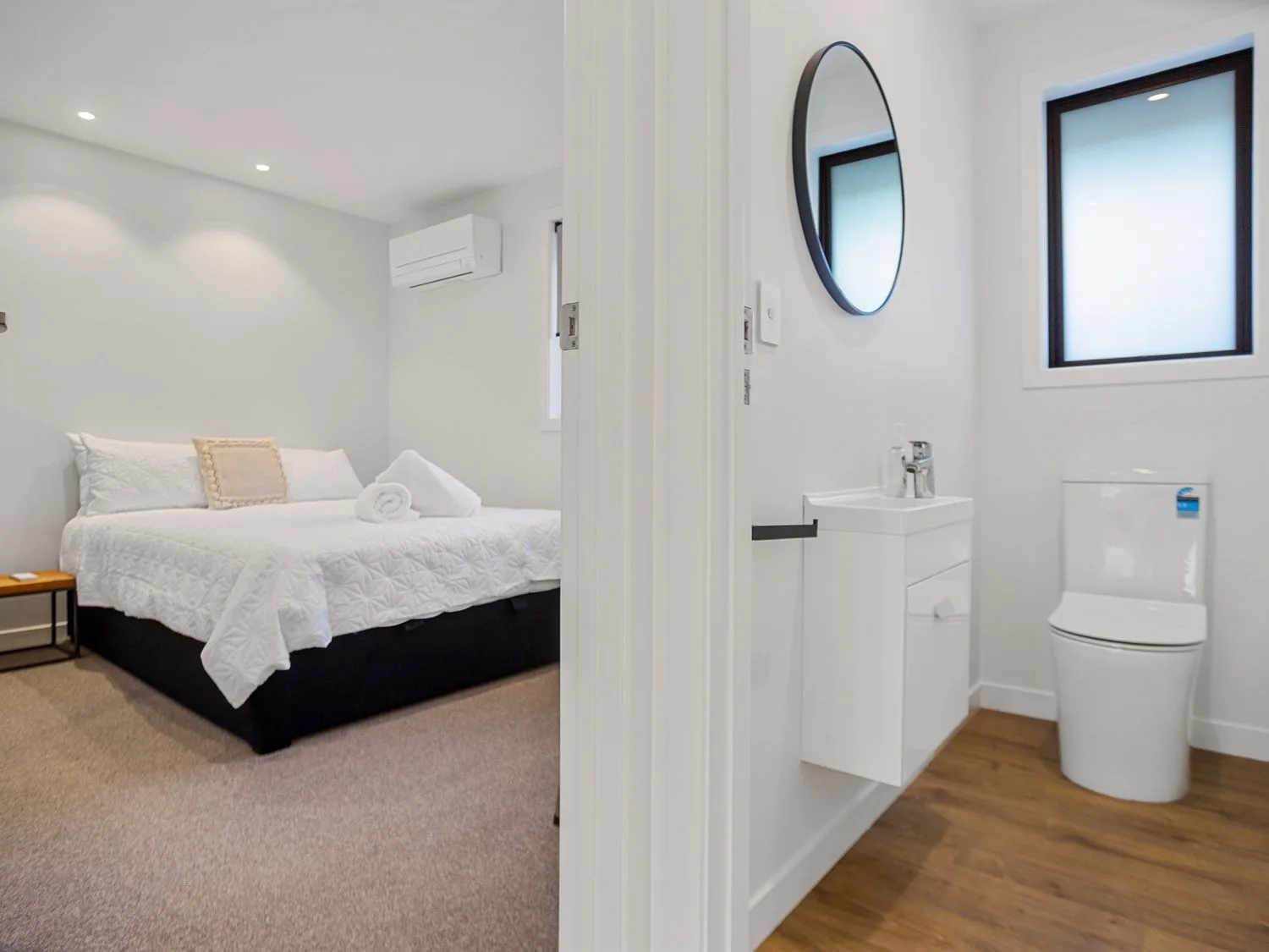 Se ve un dormitorio con una cama junto a un baño con lavabo e inodoro.