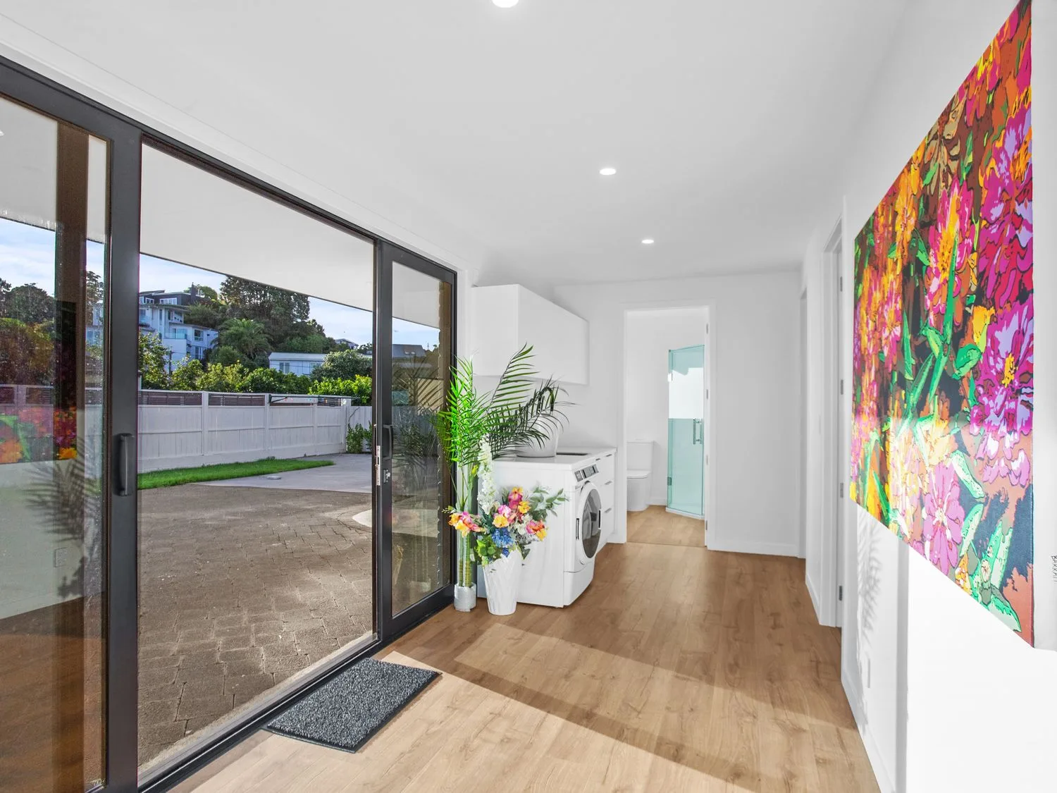 Un lavadero con una lavadora, plantas y decoración de pared colorida en Waterfront Oasis - Omokoroa Holiday Home, en Omokoroa