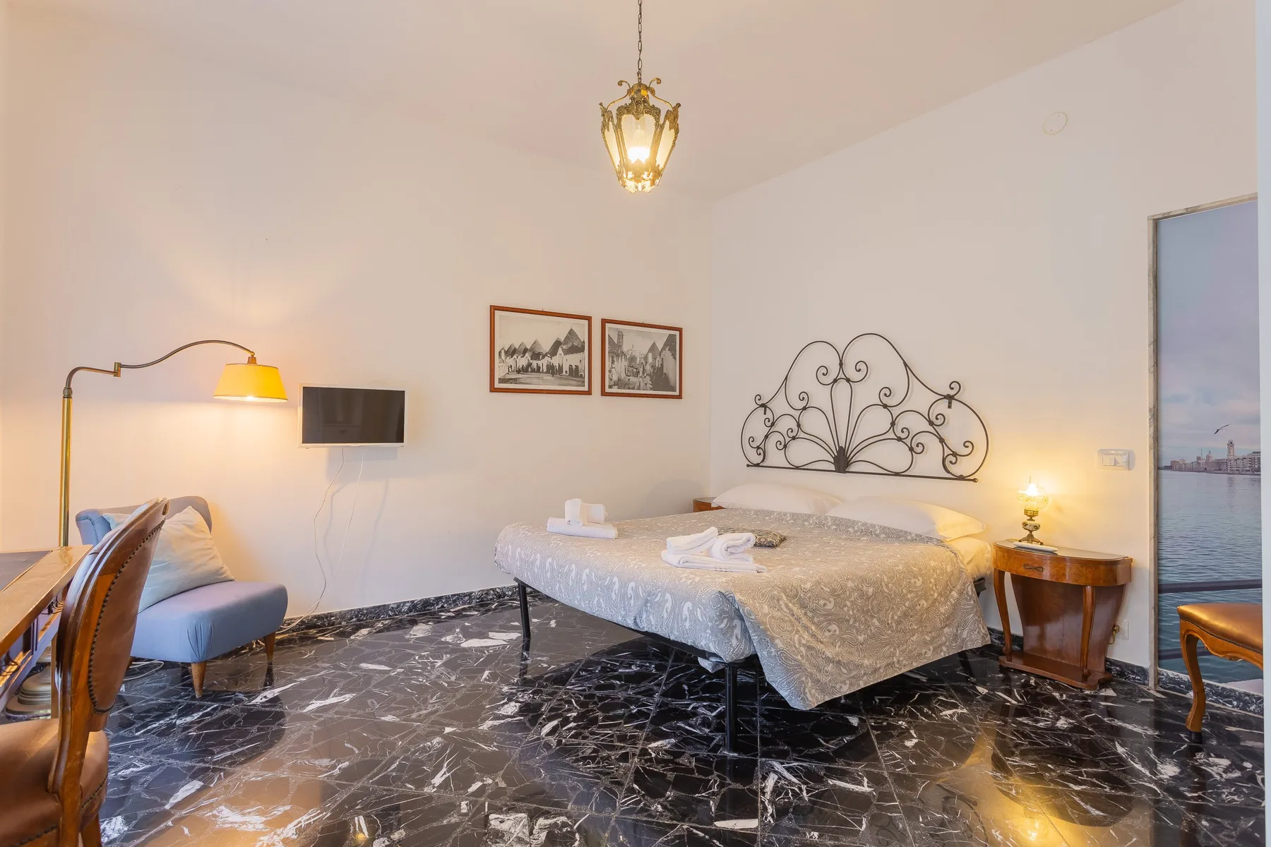 Un dormitorio con una cama doble, un cabecero de metal ornamentado y cuadros en la pared.