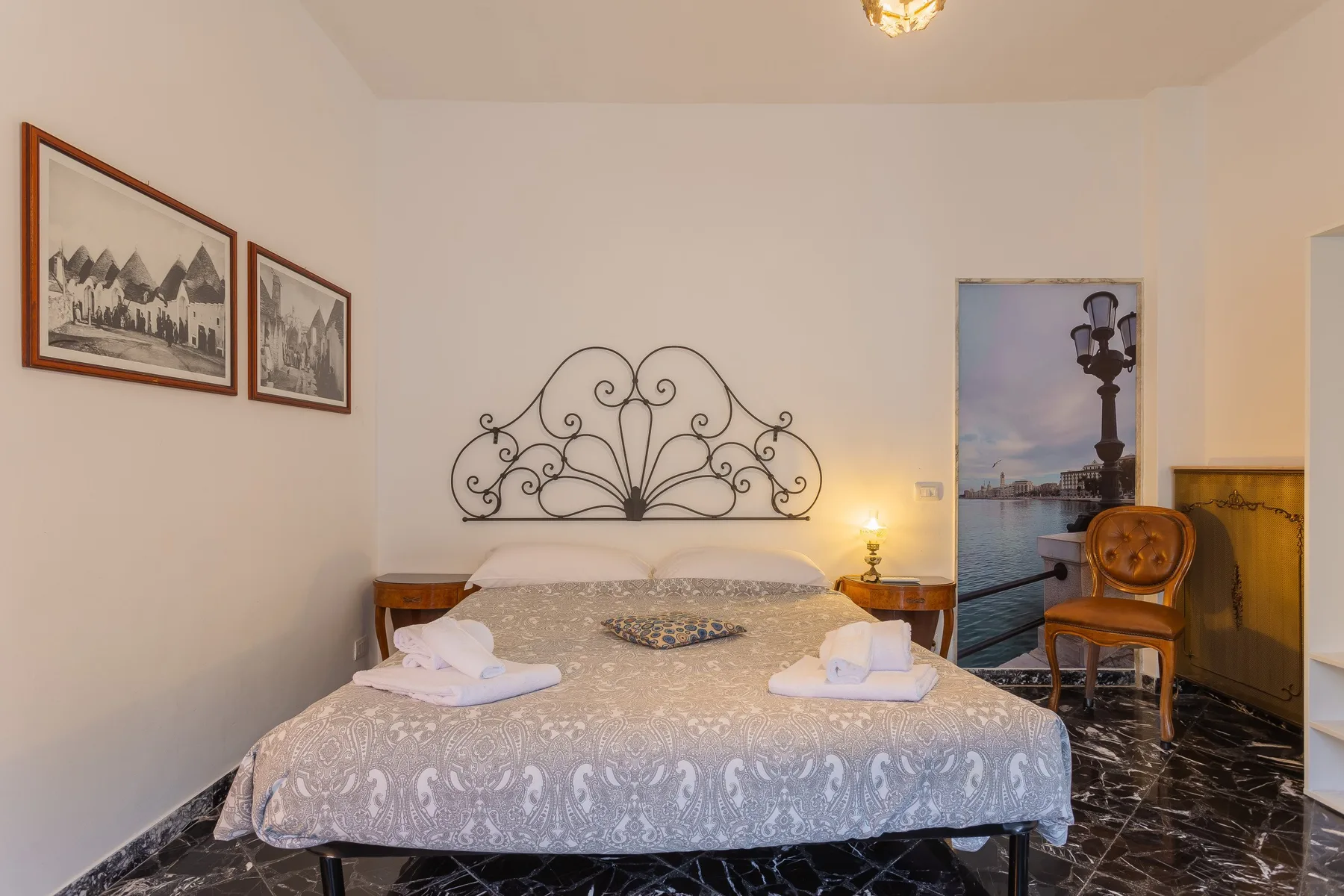 Un dormitorio con una cama doble, un cabecero decorativo de metal y cuadros en la pared.
