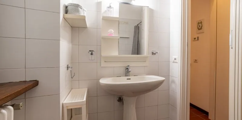 Un baño alicatado con lavabo y espejo en la pared.