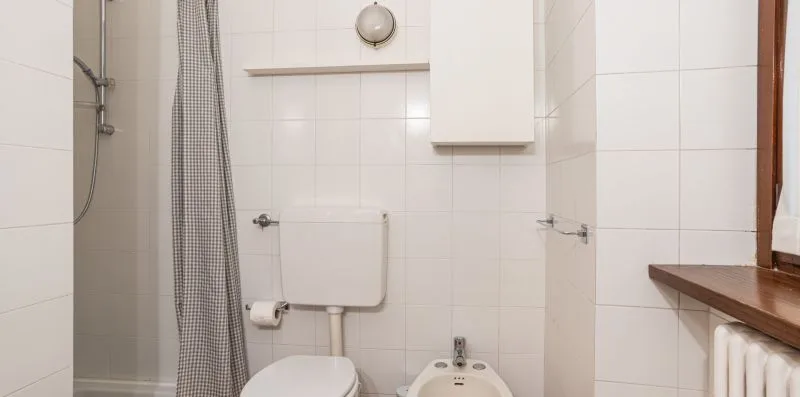 Un baño alicatado con inodoro, bidé y cortina de ducha.