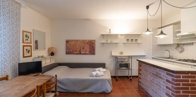 Una habitación tipo estudio con cama, asientos y una pequeña zona de cocina.