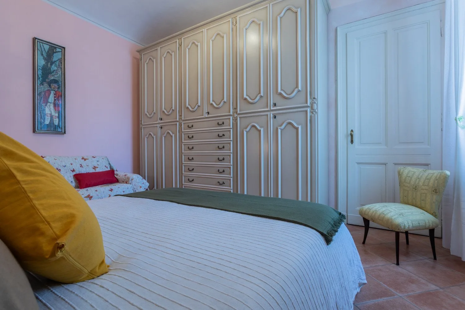 A bedroom with a bed, built-in wardrobes, and a chair beside the door.