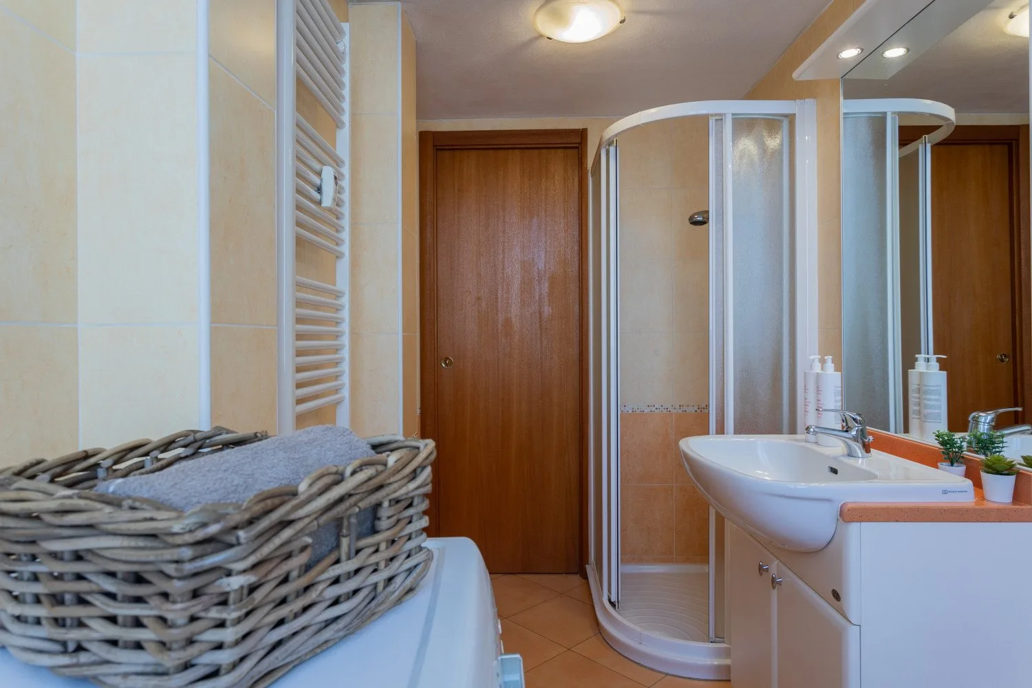 A bathroom with a curved shower enclosure and a sink beside the counter.