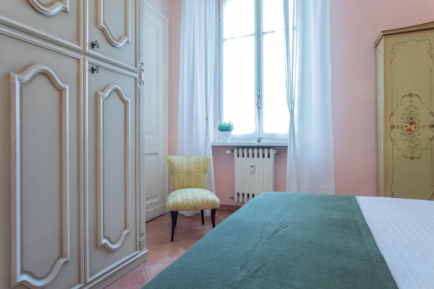 A bedroom with a bed, wardrobe, and a bright window.