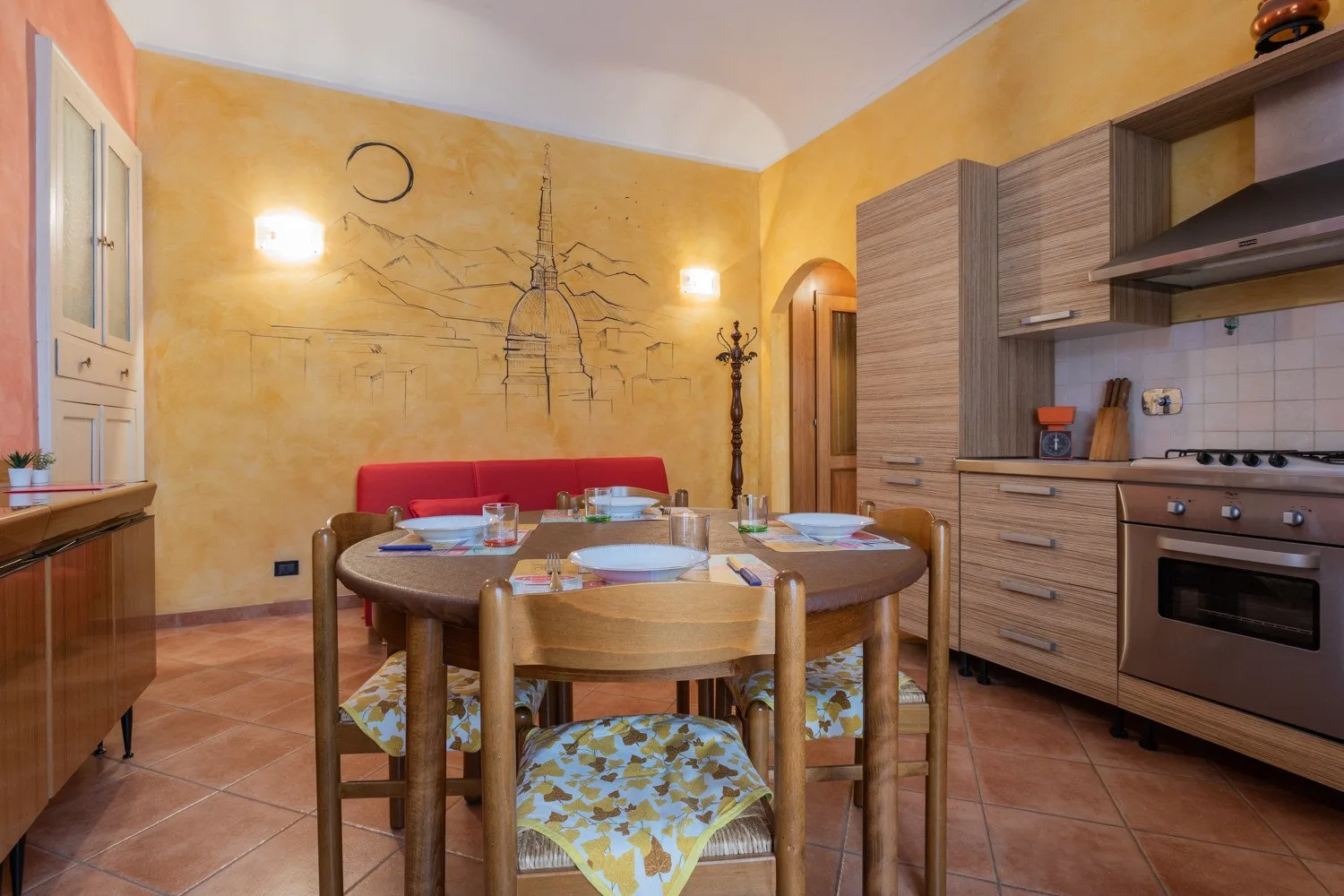 A dining area with a round table and compact kitchen along the wall.