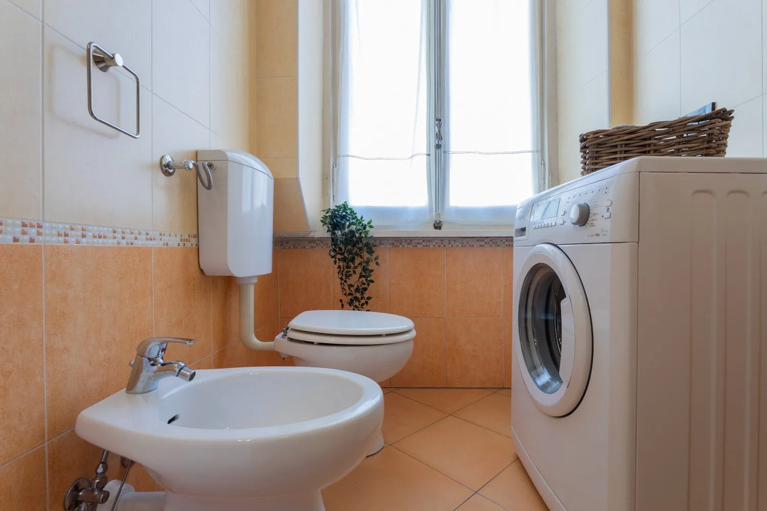 A bathroom with a toilet, bidet, sink, and washing machine.