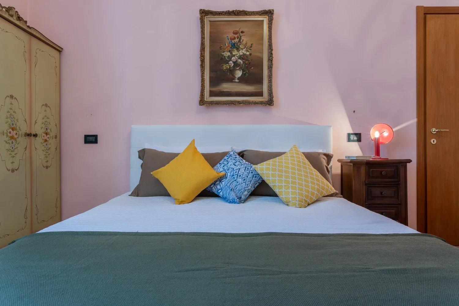 A bedroom with a neatly made bed and colorful decorative pillows.