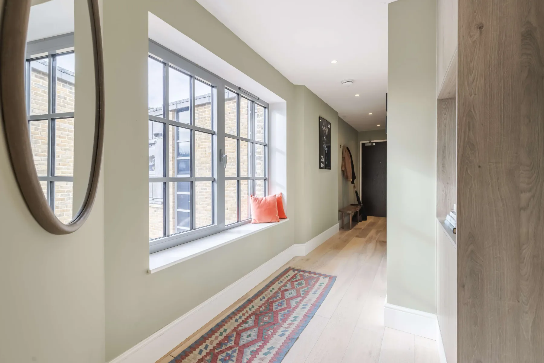 A bright hallway with large windows and a patterned runner rug.