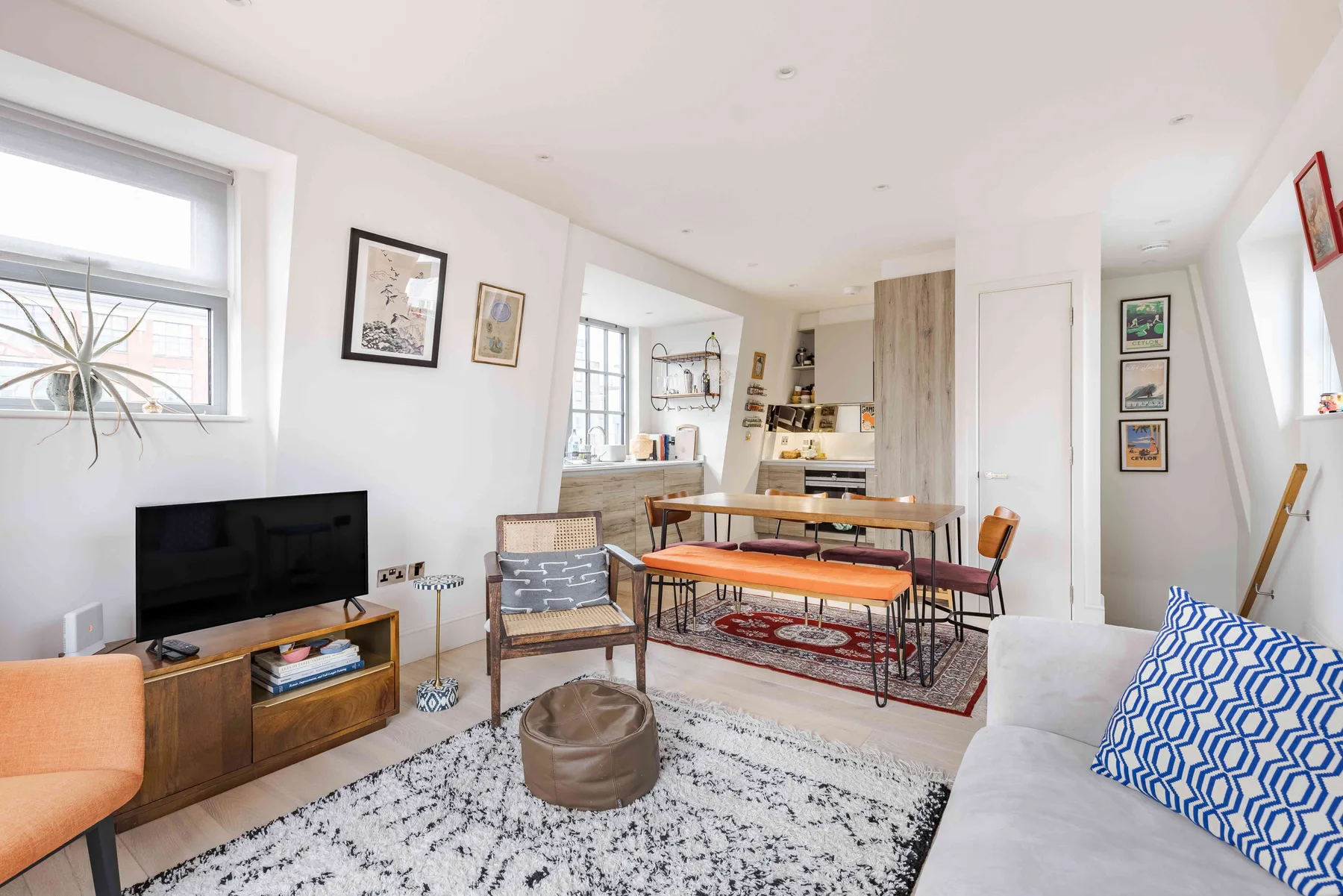 A bright living room with seating, a television, and a dining table.